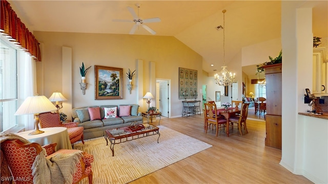 living room with high vaulted ceiling, ceiling fan with notable chandelier, and light wood-type flooring