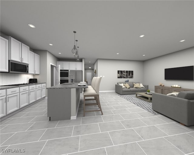 kitchen featuring a center island with sink, stainless steel appliances, white cabinetry, decorative backsplash, and a breakfast bar area