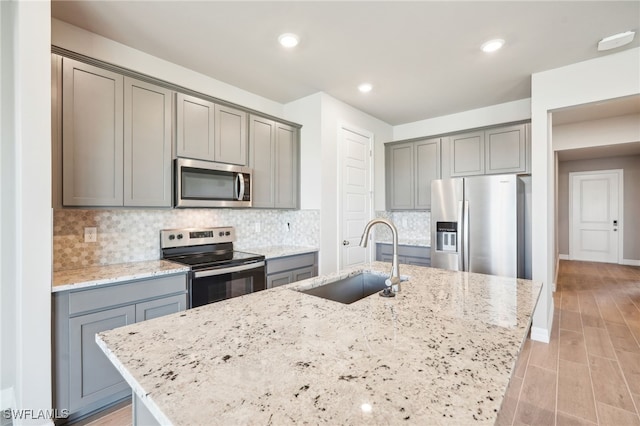 44290 Frontier Dr, Punta Gorda, FL 33982 - kitchen featuring light stone counters, appliances with stainless steel finishes, sink, and a center island with sink