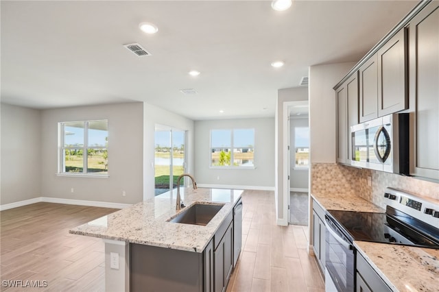 44290 Frontier Dr, Punta Gorda, FL 33982 - kitchen with sink, gray cabinetry, stainless steel appliances, light stone countertops, and a kitchen island with sink