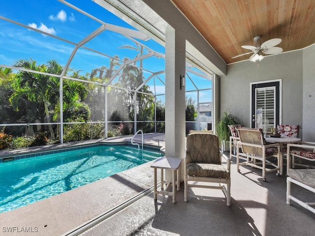 view of pool featuring glass enclosure, a patio area, and ceiling fan