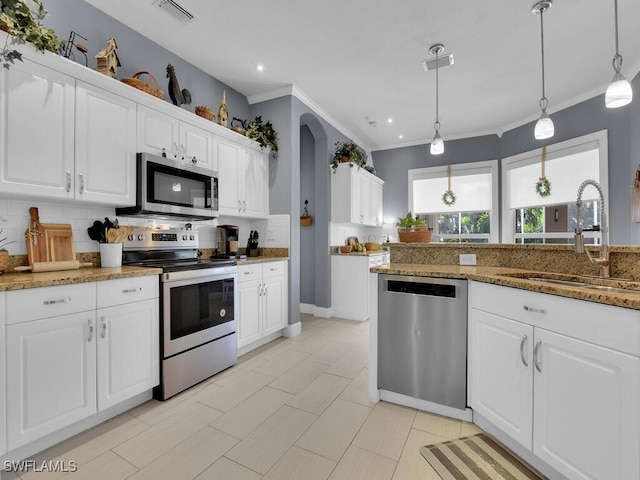 kitchen featuring pendant lighting, decorative backsplash, sink, white cabinetry, and stainless steel appliances