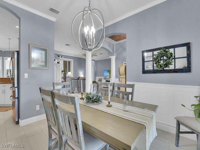 tiled dining space with decorative columns, ornamental molding, a barn door, and ceiling fan with notable chandelier