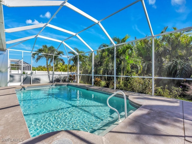 view of pool featuring glass enclosure and a patio