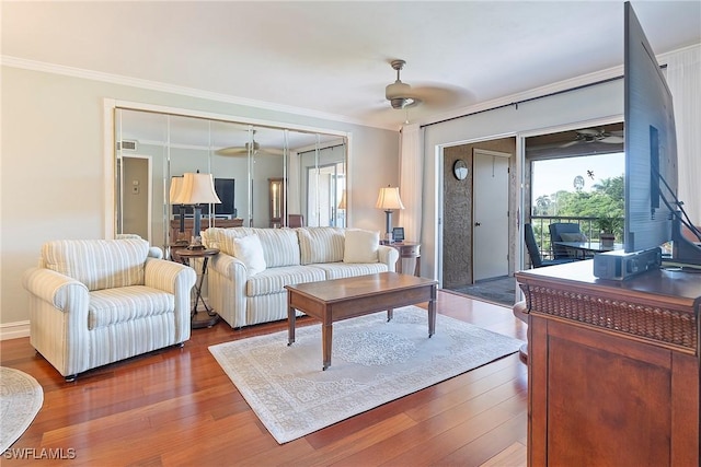 living room with ceiling fan, plenty of natural light, wood-type flooring, and ornamental molding