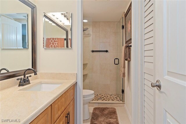 bathroom featuring toilet, walk in shower, vanity, and tile patterned flooring