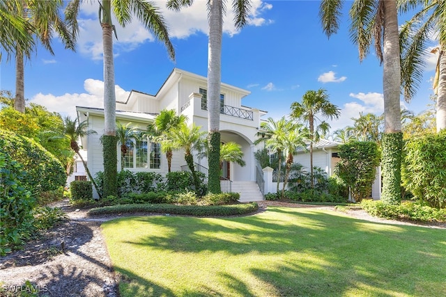 mediterranean / spanish-style home featuring a front yard and a balcony