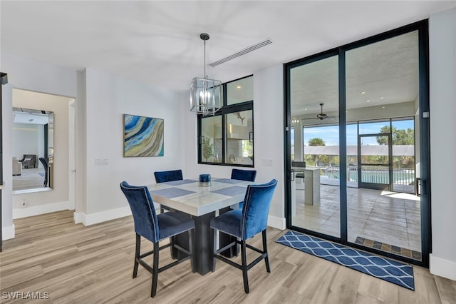 dining space featuring light hardwood / wood-style flooring, expansive windows, and ceiling fan with notable chandelier