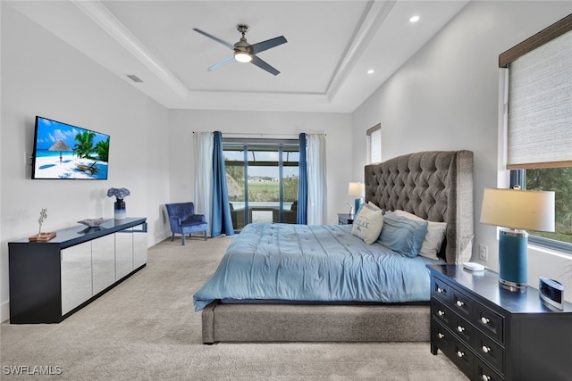 bedroom with light carpet, a tray ceiling, and ceiling fan