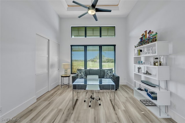 office area featuring a high ceiling, a raised ceiling, light hardwood / wood-style flooring, and plenty of natural light