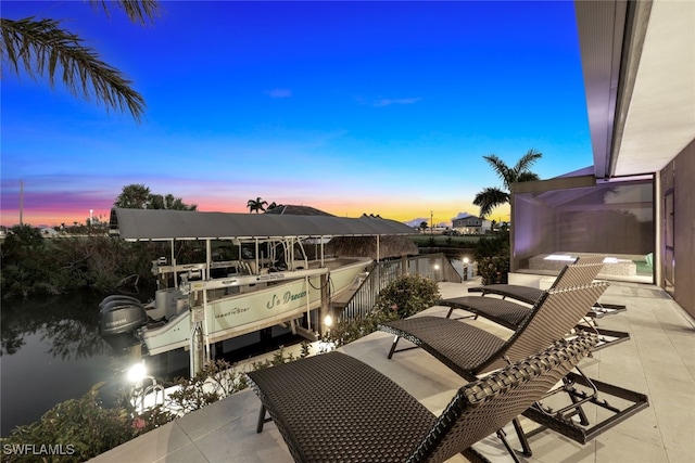 patio terrace at dusk featuring a dock and a water view