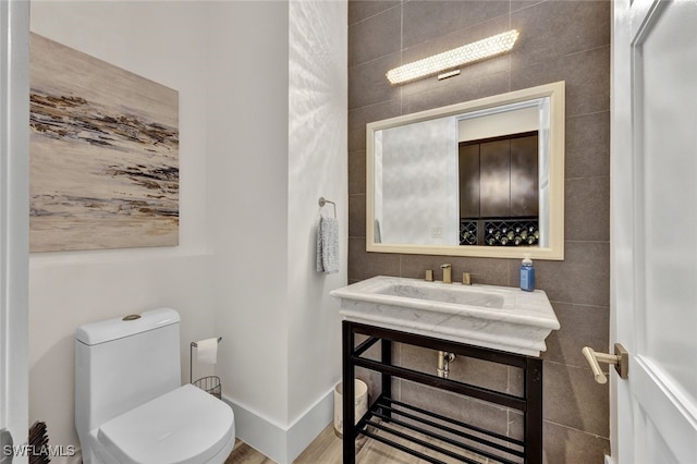 bathroom featuring hardwood / wood-style floors, toilet, tile walls, and sink