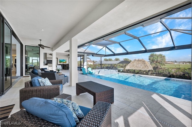 view of swimming pool featuring glass enclosure, ceiling fan, an outdoor living space, a hot tub, and a patio area