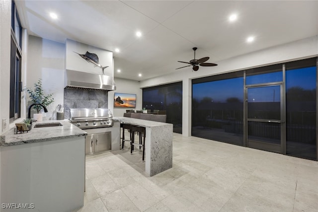 kitchen featuring backsplash, light stone counters, extractor fan, ceiling fan, and sink