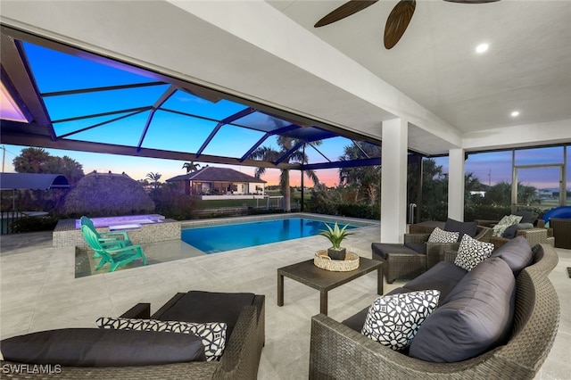 pool at dusk with a jacuzzi, an outdoor living space, a patio area, and a lanai