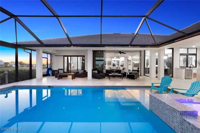 pool at dusk with a lanai, outdoor lounge area, ceiling fan, and a patio