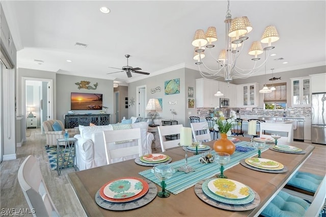 dining area with ceiling fan with notable chandelier, light hardwood / wood-style floors, and ornamental molding