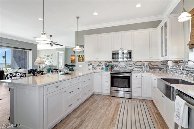 kitchen with kitchen peninsula, appliances with stainless steel finishes, ceiling fan, decorative light fixtures, and white cabinets