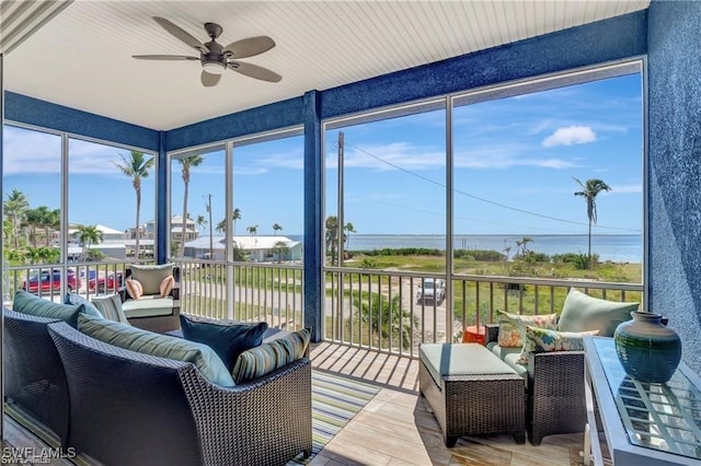 sunroom with a wealth of natural light, a water view, and ceiling fan