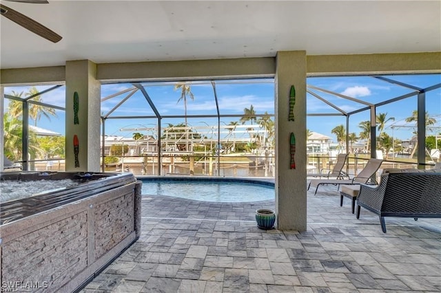 view of pool with a lanai, ceiling fan, and a water view