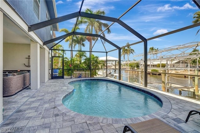 view of swimming pool with glass enclosure, a patio area, and a water view