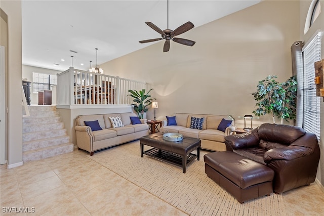 living room with ceiling fan with notable chandelier, high vaulted ceiling, and light tile patterned floors