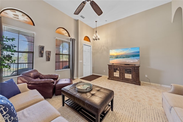 living room featuring a towering ceiling and ceiling fan with notable chandelier