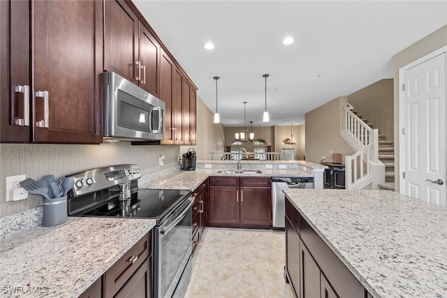 kitchen featuring kitchen peninsula, sink, light stone countertops, pendant lighting, and appliances with stainless steel finishes