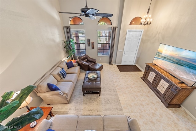 tiled living room featuring a towering ceiling and ceiling fan with notable chandelier