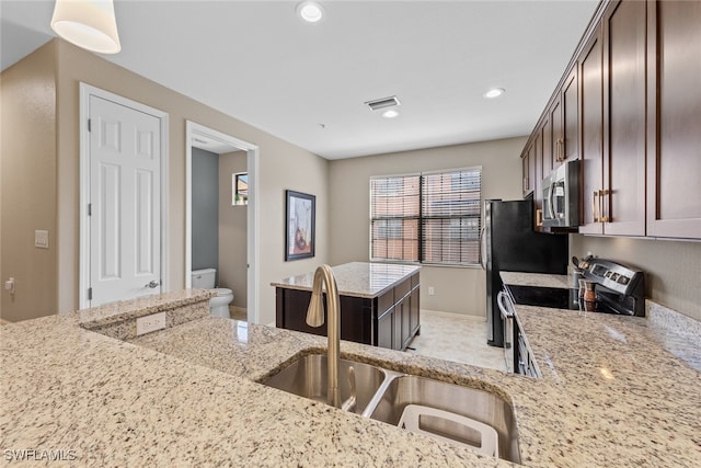 kitchen featuring sink, stainless steel appliances, dark brown cabinetry, decorative light fixtures, and light stone counters