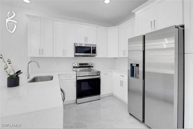 kitchen with white cabinetry, sink, hanging light fixtures, and appliances with stainless steel finishes