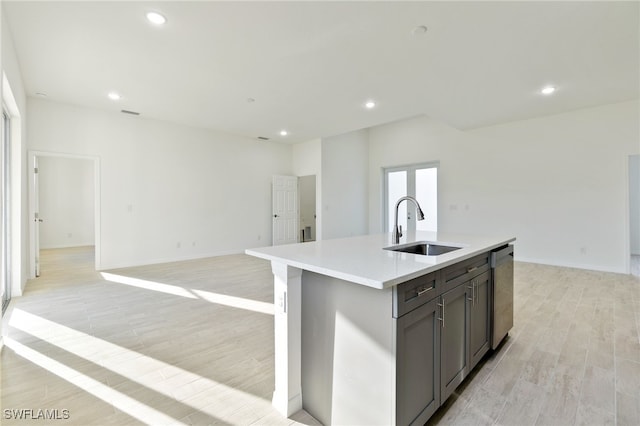 kitchen with light hardwood / wood-style floors, sink, an island with sink, and dishwasher