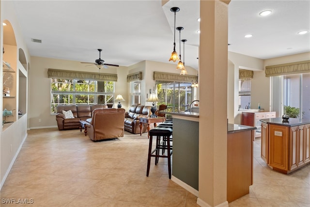 kitchen featuring a kitchen bar, decorative light fixtures, a healthy amount of sunlight, and ceiling fan