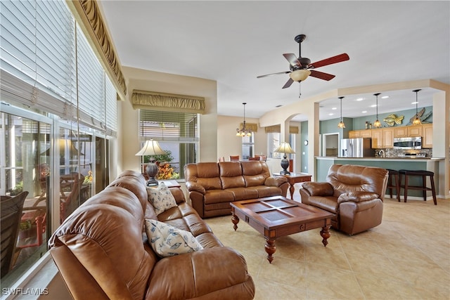 tiled living room featuring ceiling fan with notable chandelier