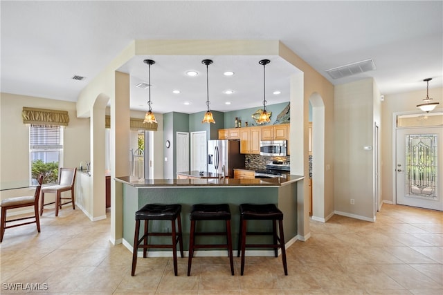 kitchen featuring a breakfast bar, tasteful backsplash, stainless steel appliances, and hanging light fixtures