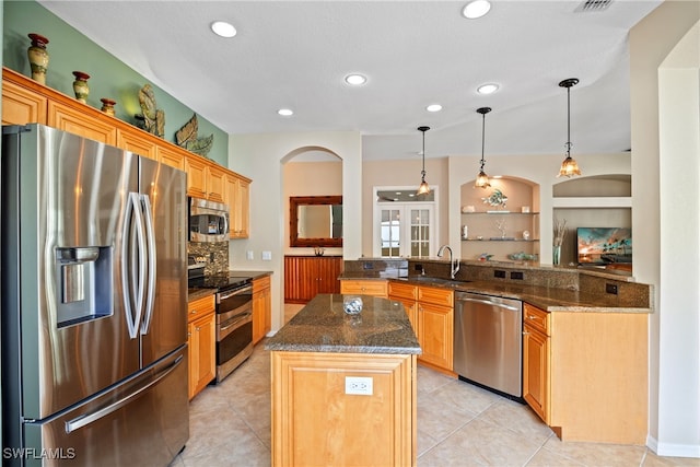 kitchen featuring hanging light fixtures, kitchen peninsula, sink, a center island, and appliances with stainless steel finishes