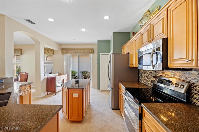 kitchen featuring a center island, stainless steel appliances, light tile patterned floors, and tasteful backsplash