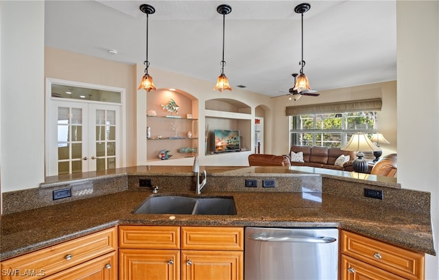 kitchen with hanging light fixtures, dishwasher, dark stone countertops, built in features, and sink