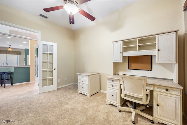 carpeted home office featuring built in desk, ceiling fan, french doors, and sink