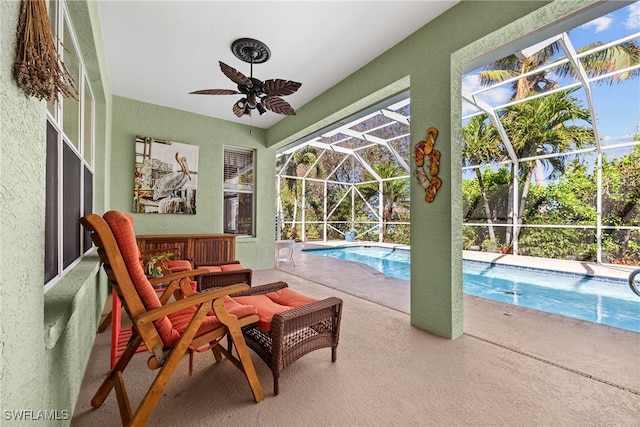 view of swimming pool with a patio, glass enclosure, and ceiling fan