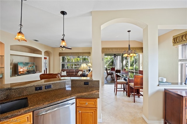 kitchen featuring dark stone countertops, lofted ceiling, stainless steel dishwasher, and hanging light fixtures