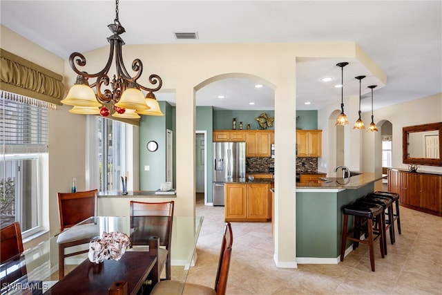 kitchen with backsplash, a healthy amount of sunlight, pendant lighting, and stainless steel refrigerator with ice dispenser