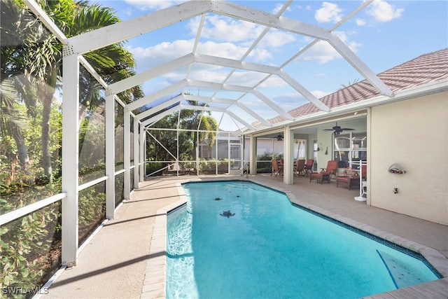 view of pool with a patio, ceiling fan, and glass enclosure