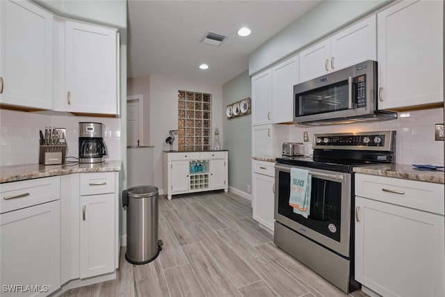 kitchen with light hardwood / wood-style floors, white cabinets, and stainless steel appliances