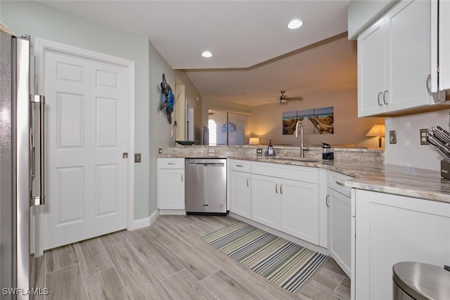 kitchen featuring kitchen peninsula, stainless steel appliances, sink, white cabinets, and light hardwood / wood-style floors