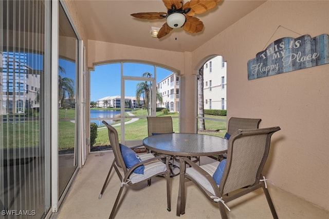 sunroom featuring a water view and ceiling fan