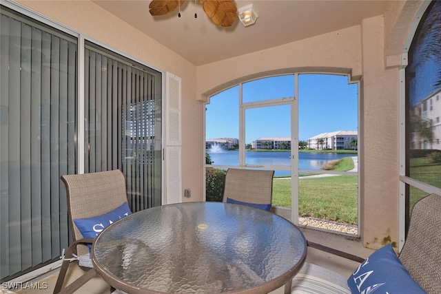 sunroom / solarium with a water view and ceiling fan