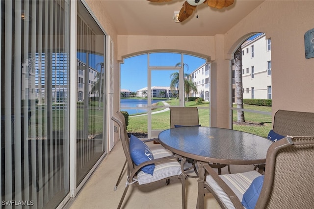 sunroom featuring a water view and ceiling fan