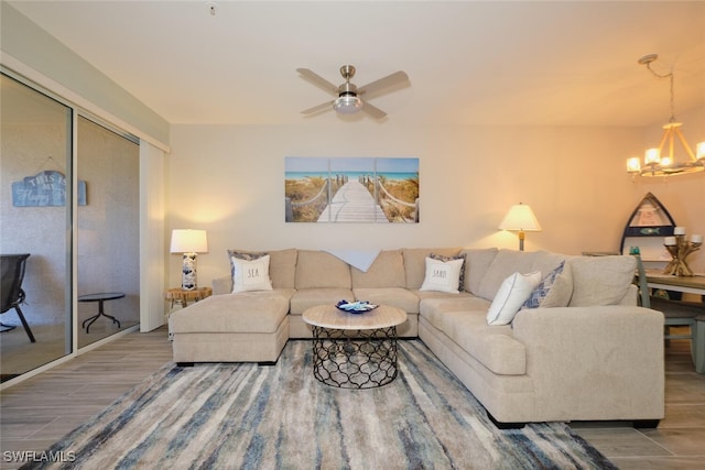 living room with ceiling fan with notable chandelier and hardwood / wood-style floors