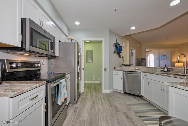 kitchen featuring white cabinetry, light stone countertops, light wood-type flooring, sink, and stainless steel appliances